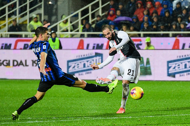 Juventus’ Argentinian forward Gonzalo Higuain shoots on goal despite Atalanta’s Dutch defender Hans Hateboer (left) during their Italian Serie A football match in Bergamo on Saturday  (AFP photo by Miguel Medina)