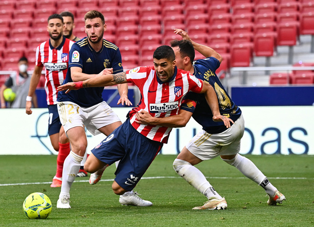 Atletico Madrid’s Uruguayan forward Luis Suarez (centre) is grabbed by Osasuna’s Spanish defender Unai Garcia (right) during their Spanish League match in Madrid on Sunday  (AFP photo by Gabriel Bouys)