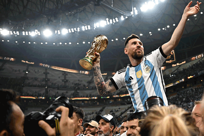Argentina’s captain and forward Lionel Messi (right) holds the FIFA World Cup Trophy after winning the final match against France in Lusail on Sunday (AFP photo by Anne-Christine Poujoulat)