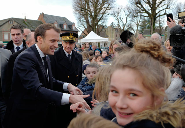 French President Emmanuel Macron shakes hands with residents before visiting a migrant centre in Croisilles, northern France, on Tuesday (AFP photo)