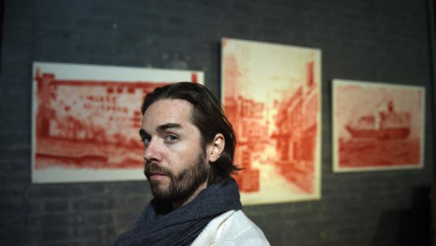 French artist Alexandre Ouairy poses in front of his paintings at the Red Gate Gallery in Beijing on November 5 (AFP photo by Greg Baker)