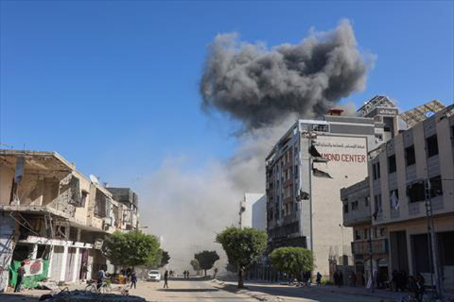 lestinians looks at smoke billowing from Israeli strikes on a makeshift displacement camp in central Gaza City on March 23, 2025  (AFP photo)