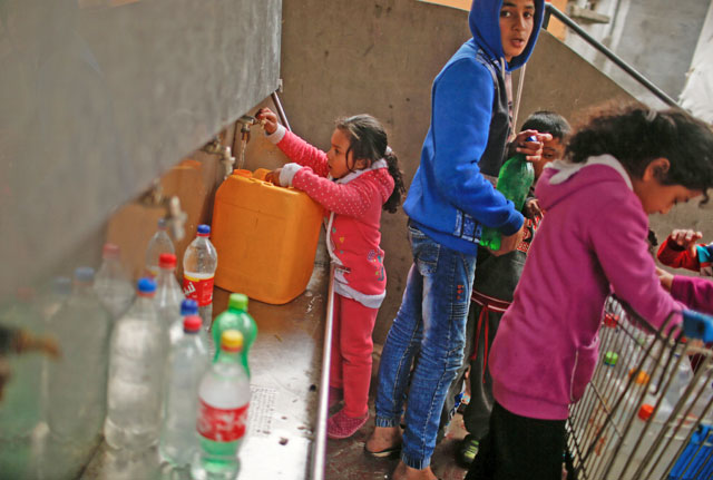 Palestinian children fill bottles and containers with drinking water from public taps in Jabaliya refugee camp in the northern Gaza Strip, on Tuesday (Reuters photo)