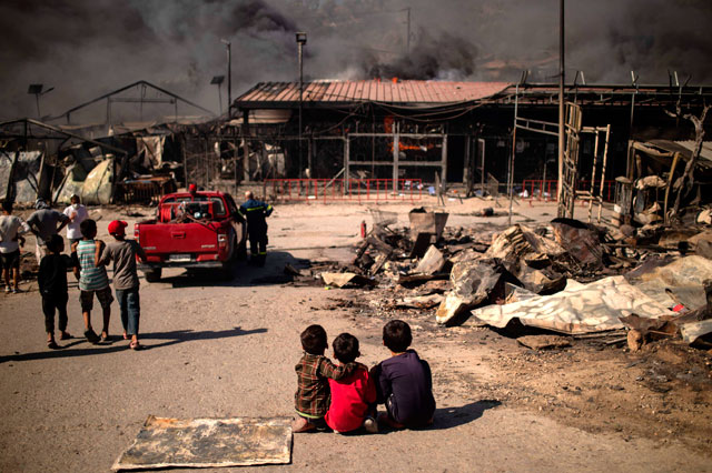 Children sit on the ground in the burnt camp of Moria on the island of Lesbos after a major fire broke out on Wednesday (AFP photo)