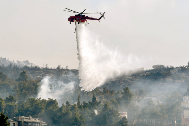 A Sikorsky S-64 Skycrane helicopter drops water over Thrakomakedones, near Mount Parnitha, north of Athens, on Saturday (AFP photo)