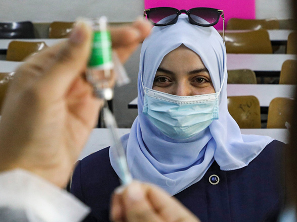 A woman waits to receive a dose of the Covishield (AstraZeneca) COVID-19 coronavirus vaccine at a school in the Palestinian city of Hebron in the occupied West Bank on Wednesday, as part of a drive to vaccinate Palestinian teachers and education ministry employees before schools reopen the following week (AFP photo)