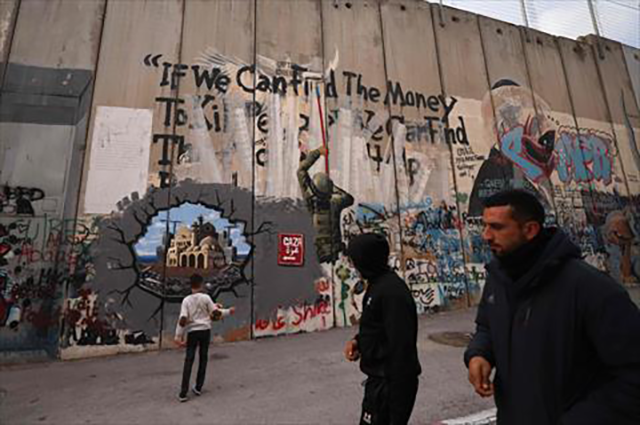 A child plays as men walk past graffiti representing the reconstruction of Gaza, on a section of Israel's separation barrier, in Bethlehem in the occupied West Bank on February 12, 2025 (AFP photo)