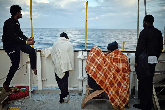 In this file photo taken on May 14, migrants look at the coastline as they stand aboard rescue ship MV Aquarius, off the coast of Sicily (AFP photo)