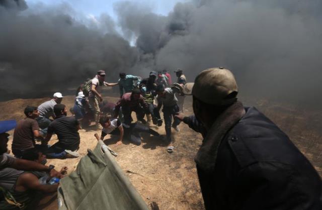  A wounded Palestinian demonstrator is evacuated as others take cover from Israeli fire and tear gas during a protest against U.S. embassy move to Jerusalem and ahead of the 70th anniversary of Nakba, at the Israel-Gaza border in the southern Gaza Strip (Reuters photo)