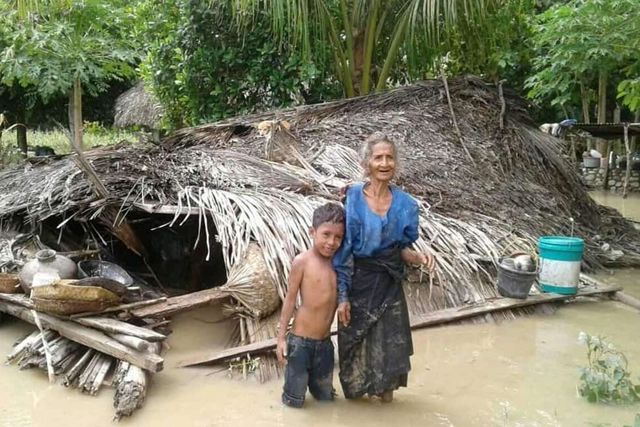 An elderly villager and her grandson stand in floodwaters in front of their damaged home in the village of Haitimuk in East Flores on Sunday, after flash floods and landslides swept eastern Indonesia and neighbouring East Timor (AFP photo)