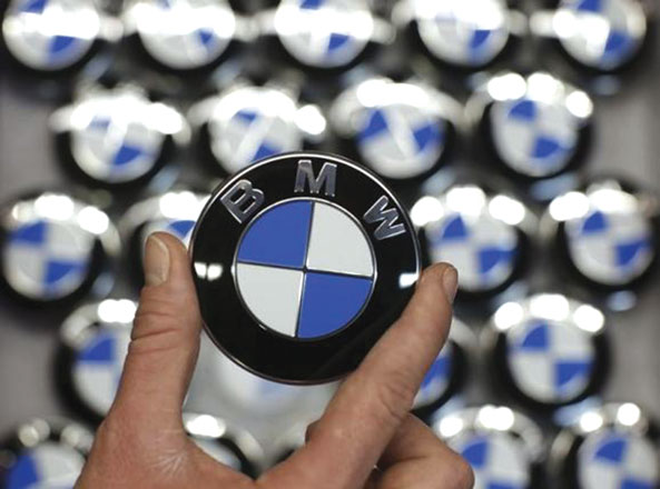 An employee holds a BMW logo on the production line of the BMW C evolution electric maxi-scooter at the BMW Berlin motorcycle plant on February 23 (Reuters photo by Fabrizio Bensch)