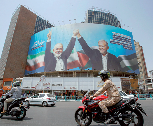 Vehicles drive past a huge billboard depicting Iranian President Masoud Pezeshkian (rught) and slain leader of the Palestinian Hamas group Ismail Haniyeh at Tehran's Valiasr Square on Thursday (AFP photo)