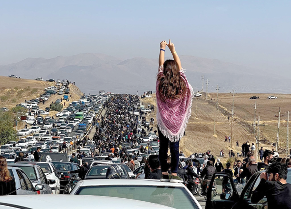 This UGC image posted on Twitter reportedly on October 26, 2022 shows an unveiled woman standing on top of a vehicle as thousands make their way towards Aichi cemetery in Saqez, Mahsa Amini's home town in the western Iranian province of Kurdistan (AFP photo)