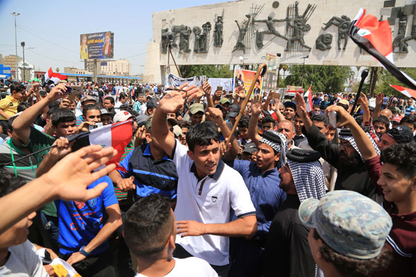 People chant anti-government slogans and wave national flags during a demonstration to protest the slow pace of reforms first promised by Prime Minister Haider Al Abadi in August 2014, in Tahrir Square, Baghdad, Iraq, on Saturday (AP photo)