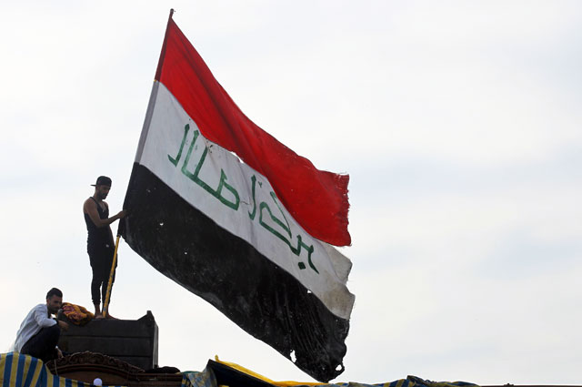 An Iraqi demonstrator waves a large national flag in the capital Baghdad's Tahrir Square, amid ongoing anti-government protests, on Friday (AFP photo)