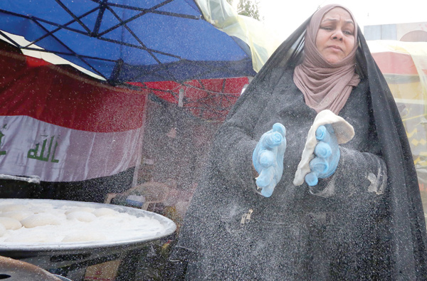 An Iraqi woman prepares traditional bread on the sidelines of ongoing anti-government protests at Tahrir Square in the capital Baghdad on Tuesday (AFP photo)