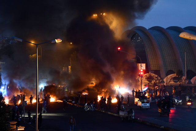 Iraqi anti-government demonstrators block a bridge with debris and burning tyres in the city of Nasiriyah in Iraq’s southern Dhi Qar province on Tuesday (AFP photo)