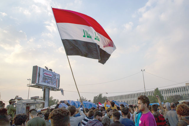 An Iraqi anti-government protester waves a national flag during a demonstration near the Basra governorate headquarters in the eponymous southern city on Friday (AFP photo)