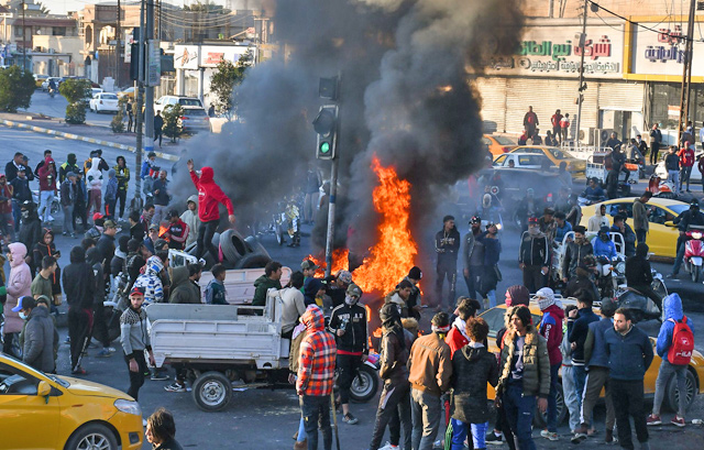 Iraqi demonstrator stand in front of burning tyres during ongoing anti-government protests in the southern Iraqi city of Nasiriyah, on Wednesday (AFP photo)