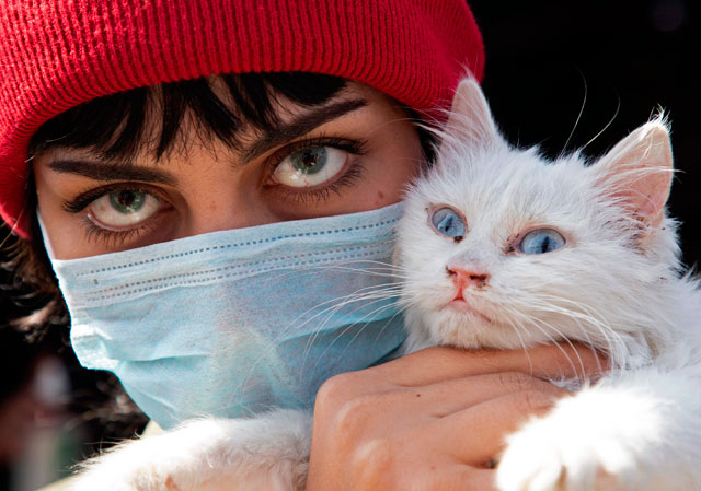 An Iraqi woman wearing a protective mask holds her cat as she poses for a picture during a protest against corruption in the Iraqi government in the southern city of Basra on Thursday (AFP photo)
