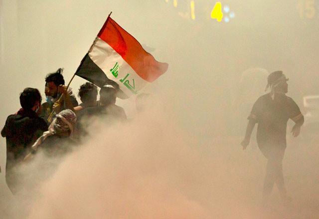Iraqi demonstrators gather amid smoke after fire services extinguished fire on tyres during a protest near the governor's residence in the southern city of Basra, to oppose assassinations and demand the resignation of top security officials in the southern Iraqi governorate, on Monday (AFP photo)