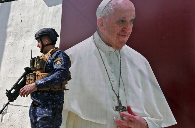 A member of the Iraqi forces stands next to a poster depicting an image of Pope Francis at the Syriac Catholic Church of Our Lady of Deliverance in the Karrada district of Iraq's capital Baghdad on Monday amidst preparations ahead of the pontiff's visit (AFP photo)