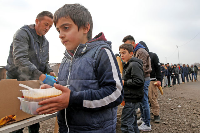 On the eve of International Migrants Day by United Nations, a young Kurdish boy from Iraq queues for food in a camp for migrants in Grand Synthe, France, on Saturday (Reuters photo)