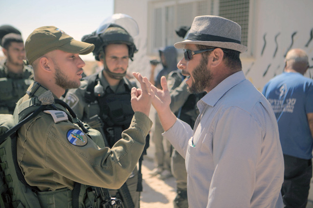 A Palestinian man talks with a member of Israeli forces while Israeli forces remove a school, made of containers by Palestinians, with help of a crane allegedly for being unauthorised near Hebron, West Bank, on Wednesday (Anadolu Agency photo)