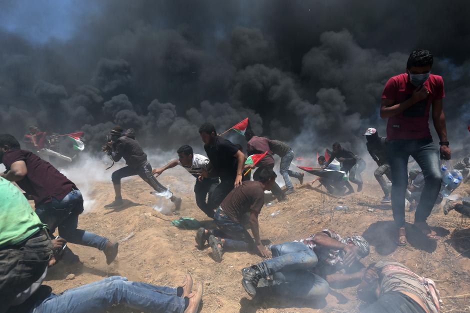  Palestinian demonstrators run for cover from Israeli fire and tear gas during a protest against US embassy move to Jerusalem and ahead of the 70th anniversary of Nakba, at the Israel-Gaza border in the southern Gaza Strip May 14, 2018 (Reuters photo)