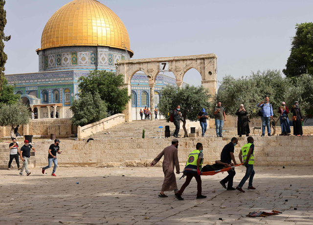 Palestinian medics walk near the Dome of the Rock as they evacuate on a stretcher a wounded protester from the Aqsa Mosque compound in Jerusalem's Old City on Monday (AFP photo)