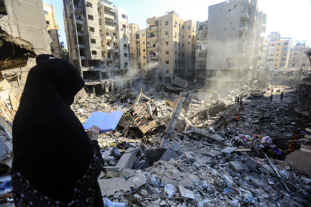  A woman reads the Holy Koran in front of the rubble of buildings which were levelled on September 27 by Israeli strikes that targeted and killed Hizbollah leader Hassan Nasrallah in the Haret Hreik neighbourhood of Beirut's southern suburbs, on September 29, 2024 (AFP photo)