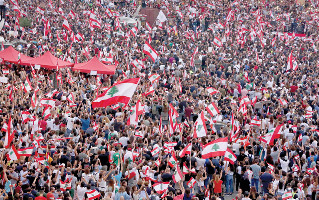 Lebanese demonstrators wave national flags as they take part in a rally in the capital Beirut's downtown district on Sunday. Thousands continued to rally despite calls for calm from politicians and dozens of arrests (AFP photo)