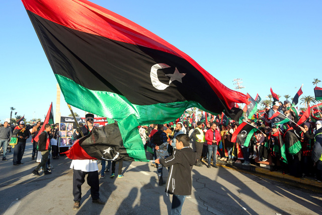 Libyans wave the national flag as they commemorate the ninth anniversary of the uprising against former Libyan leader Muammar Qadhafi, in the capital Tripoli, on Monday (AFP photo)