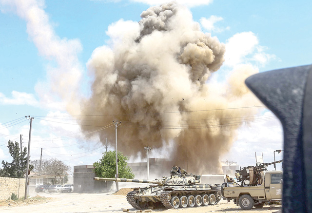 A smoke plume rises from an air strike behind a tank and technicals (pickup trucks mounted with turrets) belonging to forces loyal to Libya's Government of National Accord during clashes in the suburb of Wadi Rabie, south of the capital Tripoli, in April 2019 (AFP photo)