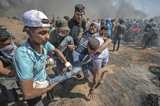 Palestinians carry a protester injured by Israeli occupation forces during a demonstration organised to mark the 70th anniversary of the Nakba, or ‘the catastrophe’, when thousands were forced to flee their homes amid violence surrounding the creation of Israel in 1948, near the Israeli border in the eastern part of Shujaiyya neighbourhood of Gaza City, Gaza, on Monday (Anadolu Agency photo)