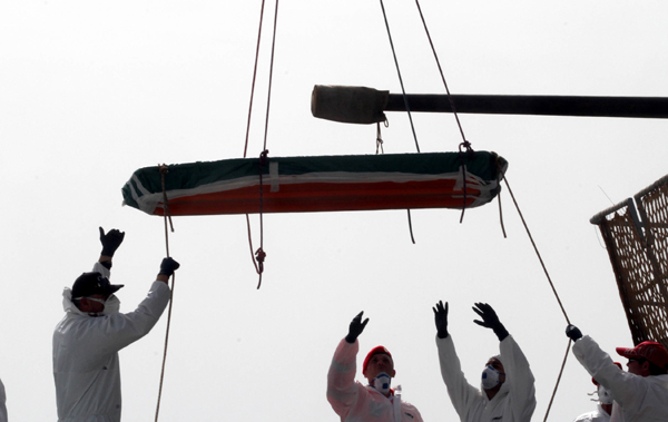 One of the 45 bodies of migrants that were recovered by the Italian military ship Vega during its search and rescue mission in the Mediterranean sea, is being disembarked at the harbour of Reggio Calabria, Southern Italy, on Sunday (AP photo)