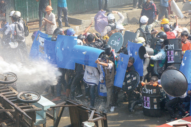 Protesters react behind shields as water cannon is fired at them by police during a demonstration against the military coup in the northwestern town of Kale on Tuesday (AFP photo)