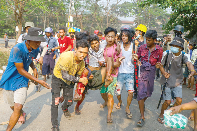 A resident, who was injured during a crackdown by security forces on demonstrations by protesters against the military coup, is carried to safety in Yangon's Hlaing Tharyar township on Sunday (AFP photo)