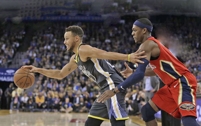 Golden State Warriors guard Stephen Curry drives the ball away from New Orleans Pelicans guard Rajon Rondo (right) during their NBA game in Oakland, California, on Monday (Reuters photo)