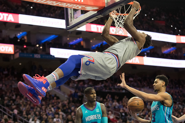 Philadelphia 76ers centre Joel Embiid dunks and hangs on the basket against Charlotte Hornets guard Jeremy Lamb during their NBA game in Philadelphia on Friday  (Reuters photo by Bill Streicher)