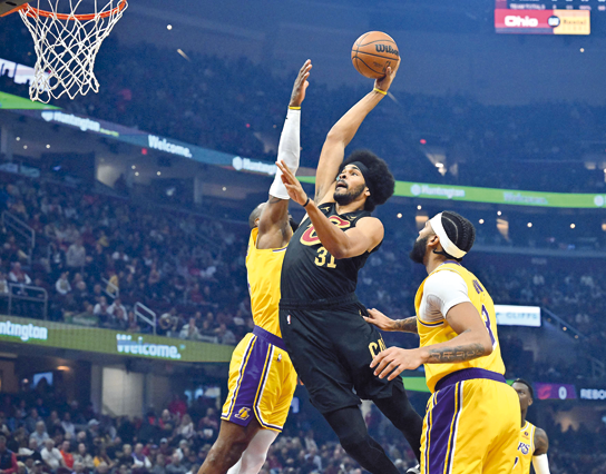 Jarrett Allen of the Cleveland Cavaliers dunks over LeBron James and Anthony Davis (right) of the Los Angeles Lakers during their NBA game first in Cleveland, Ohio, on Tuesday (AFP photo by Jason Miller)