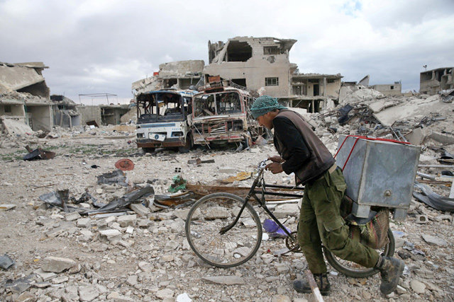 A man walks with his bicycle at a damaged site in the besieged town of Douma, Eastern Ghouta, in Damascus, Syria, on Friday (Reuters photo)