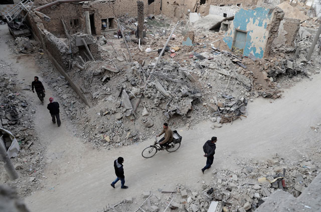 Syrians walk past the rubble of destroyed buildings in the rebel-held town of Douma, on the eastern outskirts of the capital Damascus, on Monday  (AFP photo )