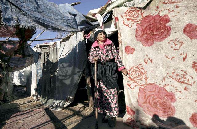 A Palestinian woman stands next to her home near the site of an Israeli air strike the previous night in Gaza City on Thursday (AFP photo)