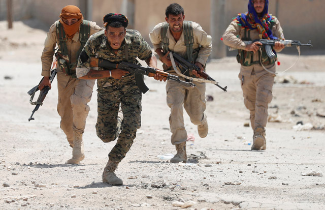 Kurdish fighters from the People’s Protection Units run across a street in Raqqa, Syria, Monday (Reuters photo)