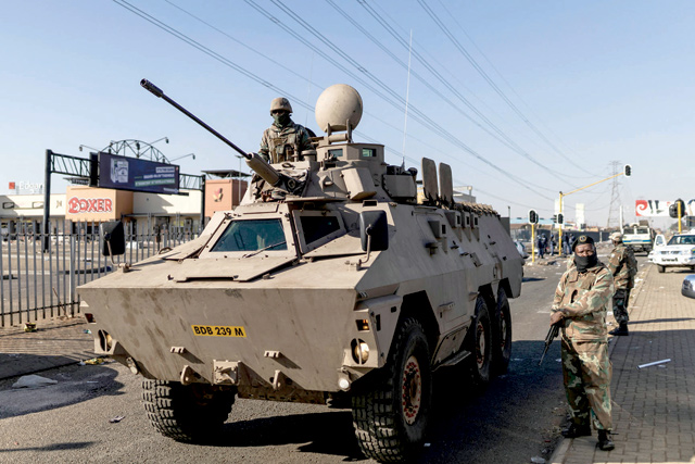 Members of the South Africa Defence Force stand guard with an armoured vehicle outside the Chris Hanni Mall in Vosloorus, on the northern outskirts of Johannesburg, on Wednesday (AFP photo)