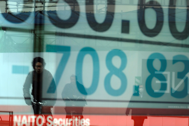 People are reflected in a window showing a drop in share price numbers on the Tokyo Stock Exchange on March 30, 2020, in Tokyo (AFP photo)