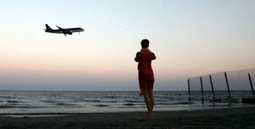  This tourist takes photos on a beach while an airplane prepares to land in Cyprus on October 22, 2017 (Reuters photo by Yiannis Kourtoglou)