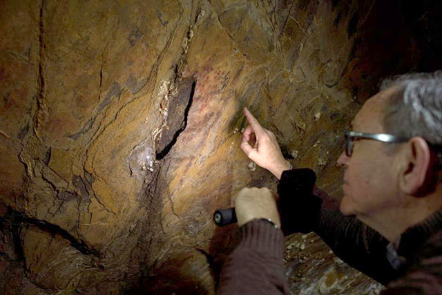 Pedro Cantalejo, director of the Andalusian cave of Ardales, looks at Neanderthal cave-paintings inside the cavern on March 1, 2018 (AFP photo by Jorge Guerrero)