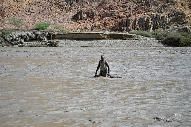 A Sudanese man wades through muddy waters after the collapse of the Arbaat Dam, 40km north of Port Sudan following heavy rains and torrential floods on August 25, 2024 (AFP photo)